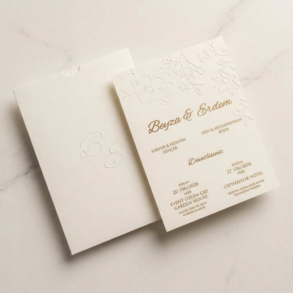 Luminae floral ivory wedding invitation featuring embossed botanicals and gold foil calligraphy on linen paper.