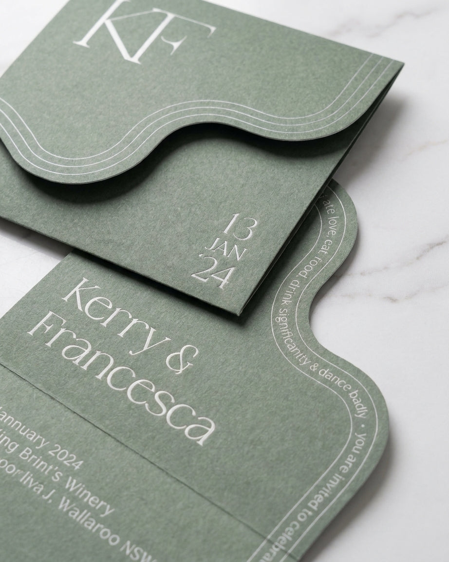 Sage green Verdura wedding invitation with a unique wavy edge and elegant white monogram on matte luxury paper.