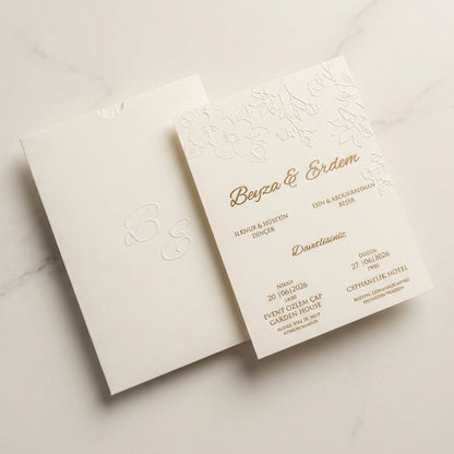 Luminae floral ivory wedding invitation featuring embossed botanicals and gold foil calligraphy on linen paper.