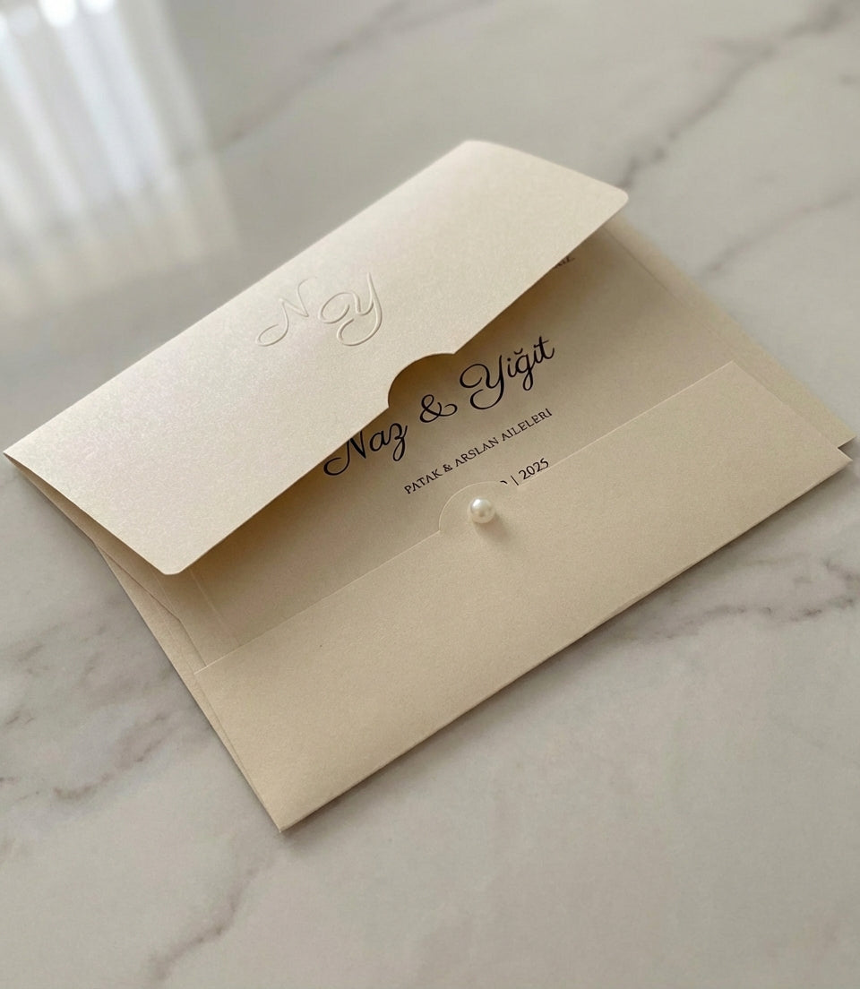 Celestina cream wedding invitation featuring a nacreous shimmer pocket, embossed monogram, and elegant pearl detail.