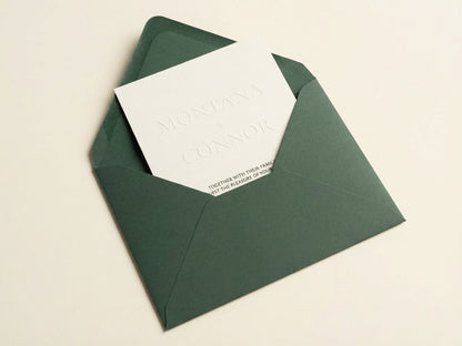 Althea embossed wedding invitation with ivory cardstock inside a deep forest green luxury envelope.